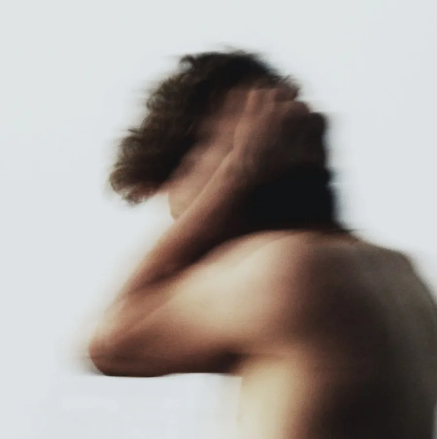 A blurred figure in profile, hand raised near the head