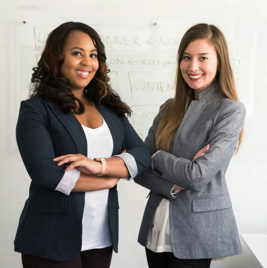 Two colleagues standing in front of a whiteboard, arms folded