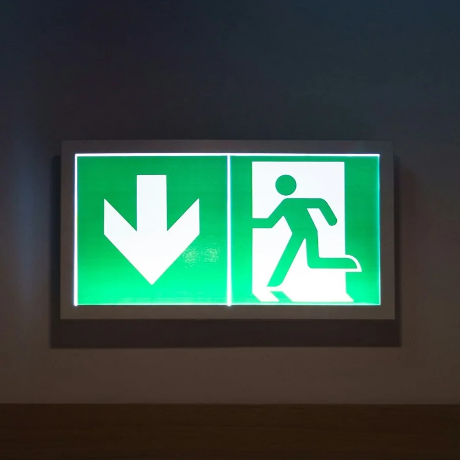 A lit emergency exit sign in a dark corridor