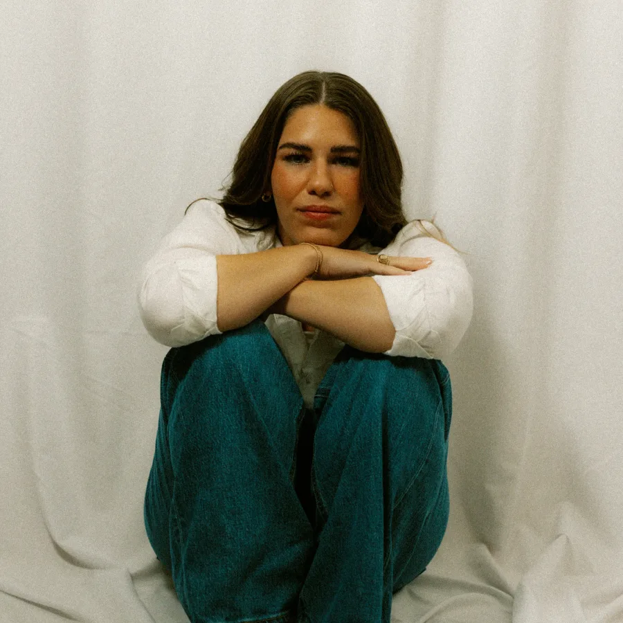 Young woman sitting on the floor, arms wrapped around her knees