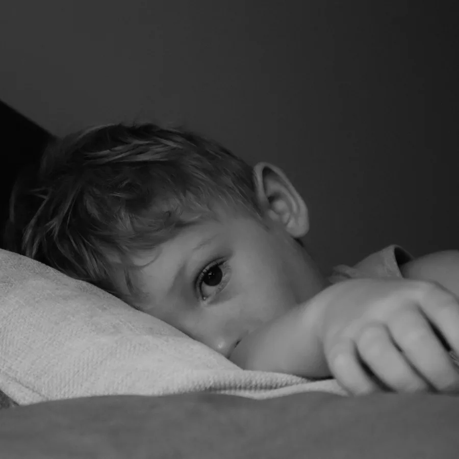Jeune enfant allongé dans son lit le soir, les yeux grands ouverts