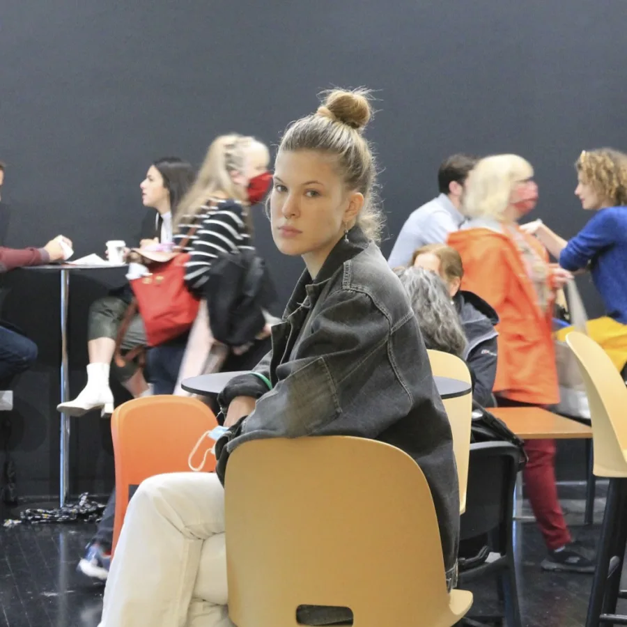 Une personne assise à l'écart dans une salle, un groupe qui discute derrière elle