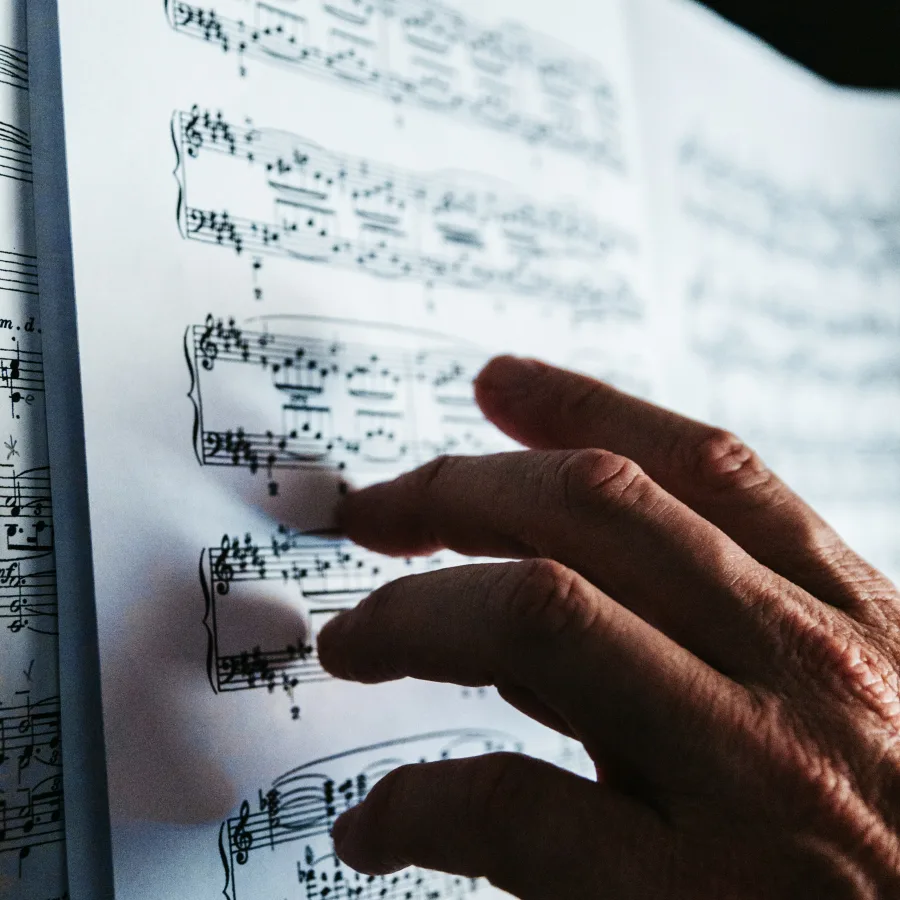 A hand resting on a piano score in raking light