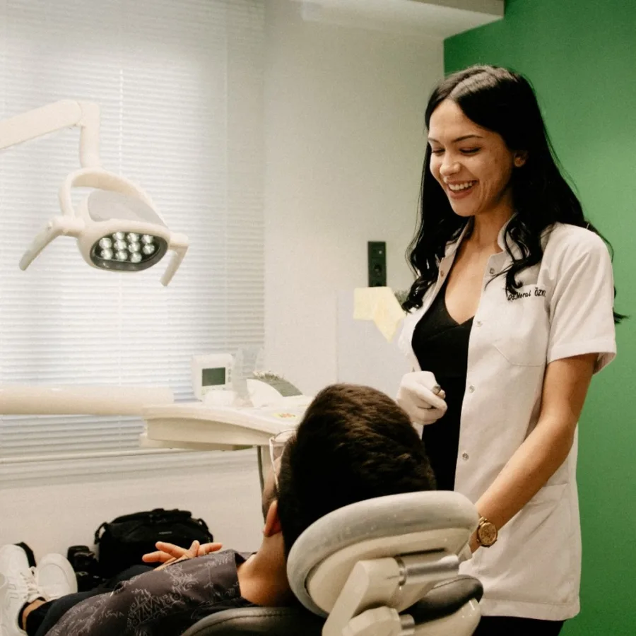 Una dentista sonriente junto a una persona instalada en el sillón