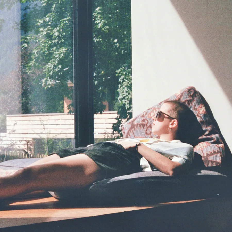 Person lying in daylight, arms behind the head, shoulders relaxed
