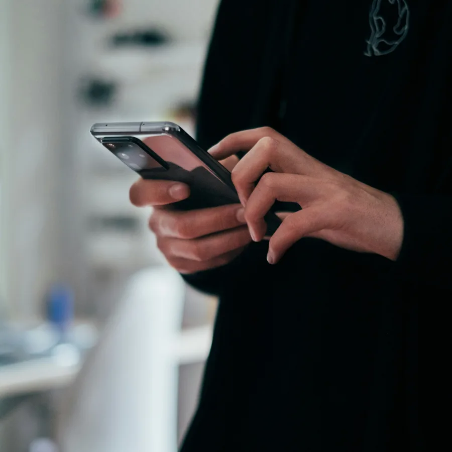 Des mains qui tiennent un téléphone dans la pénombre d'un appartement