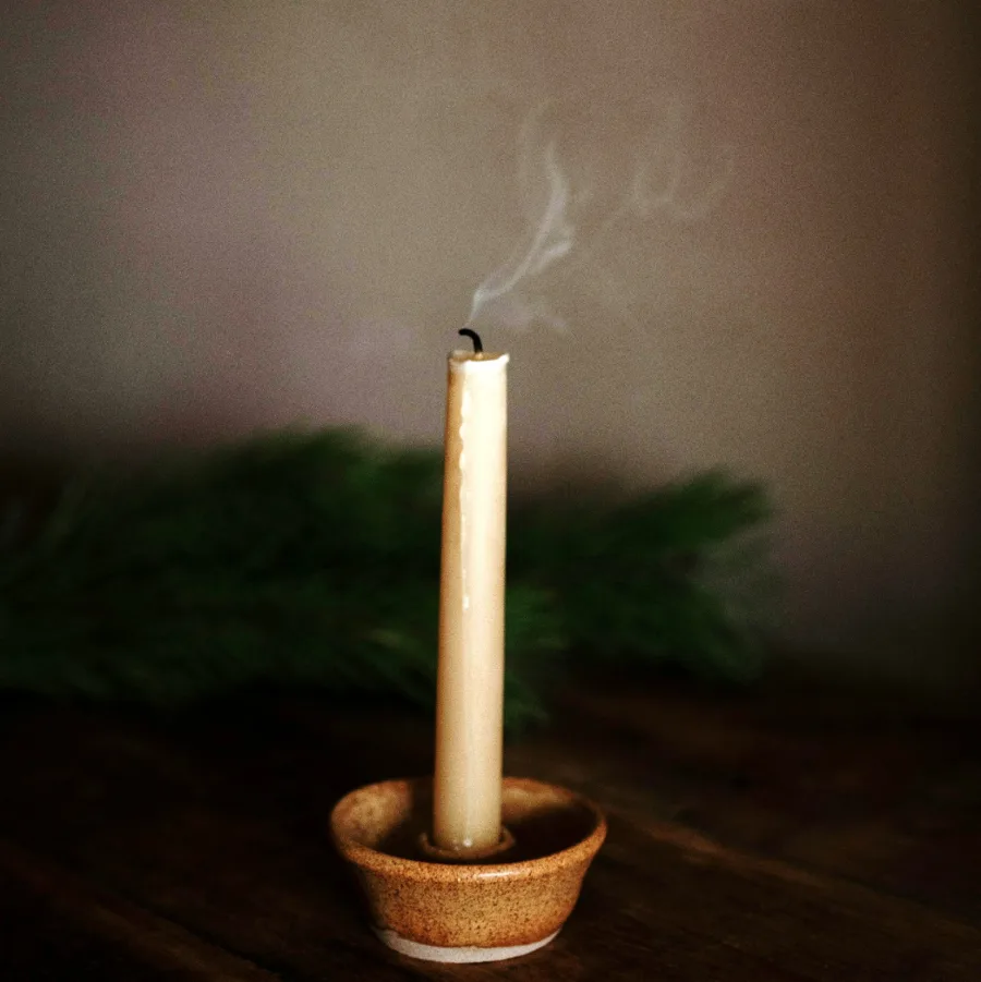 A candle just blown out, a thread of smoke above the wick