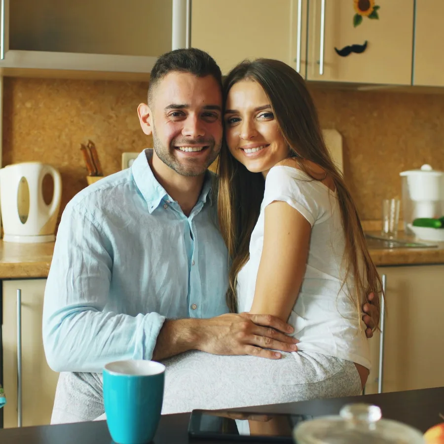 Couple, fully dressed and at ease, smiling in a bright kitchen