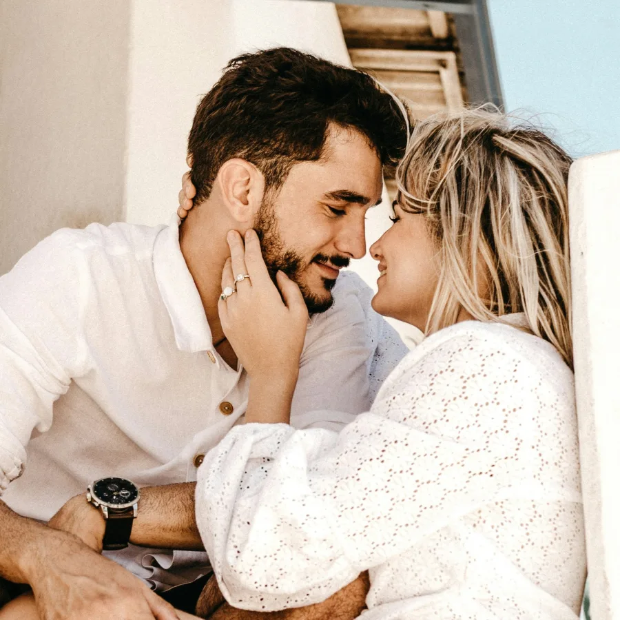 Pareja vestida y cómplice, frente con frente, en una luz clara