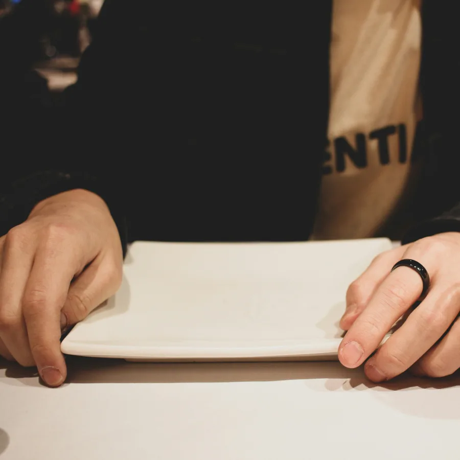 Unas manos dejando un plato vacío sobre una mesa de restaurante