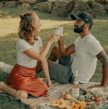 Shared picnic on the grass, two people sitting on a blanket