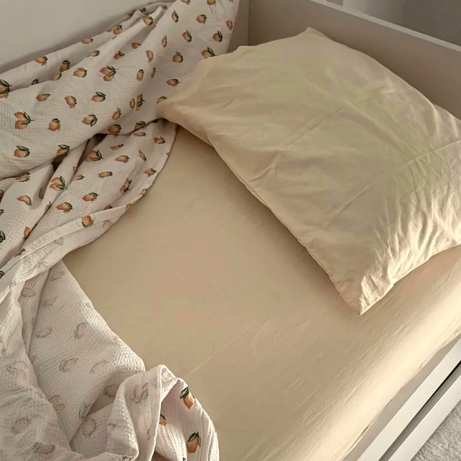 A child's bed in the early morning, covers pulled back and the pillow empty