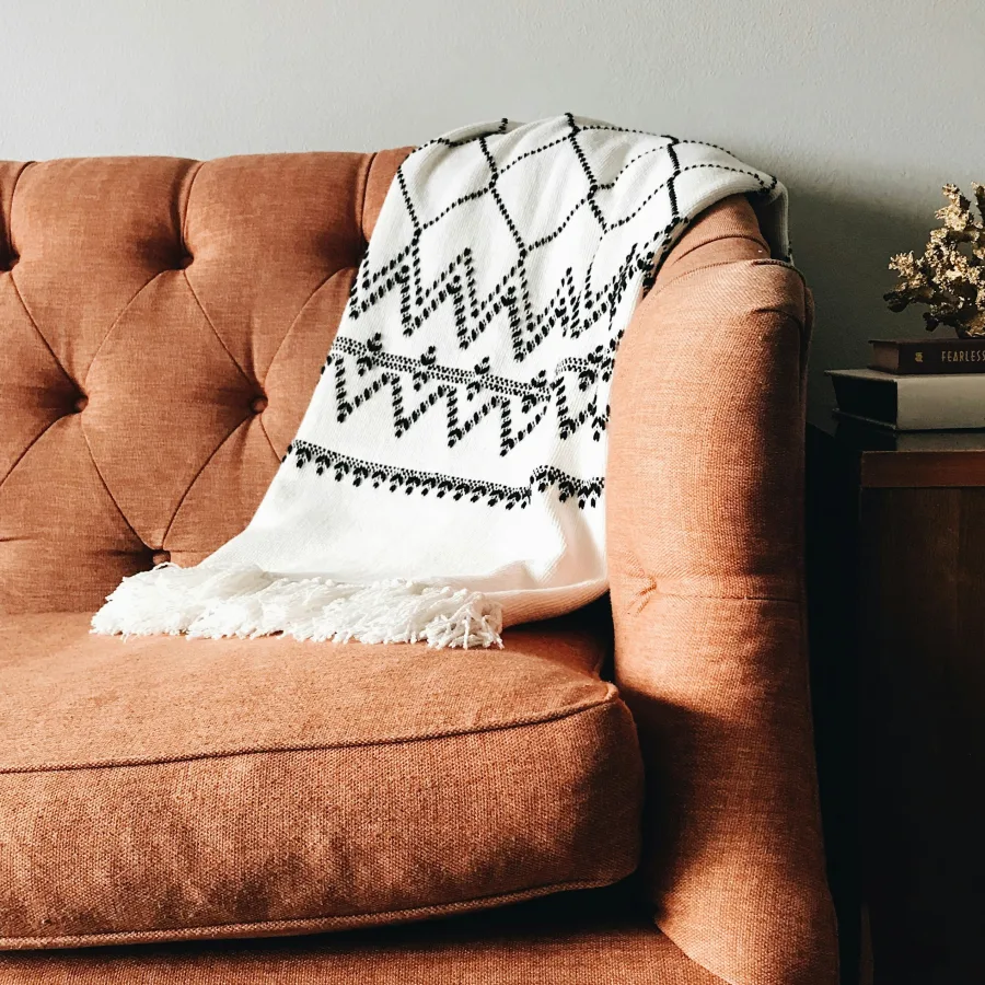 Un plaid blanc posé sur un fauteuil terracotta, dans un intérieur calme