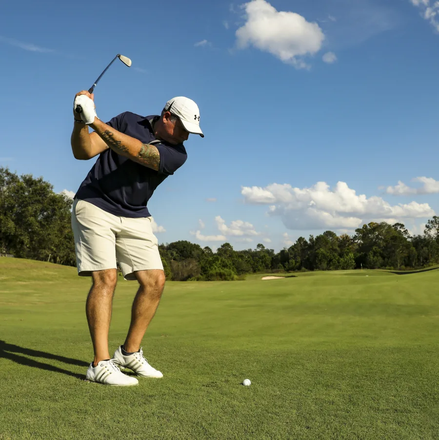 Golfer at the top of his backswing on a course in clear weather
