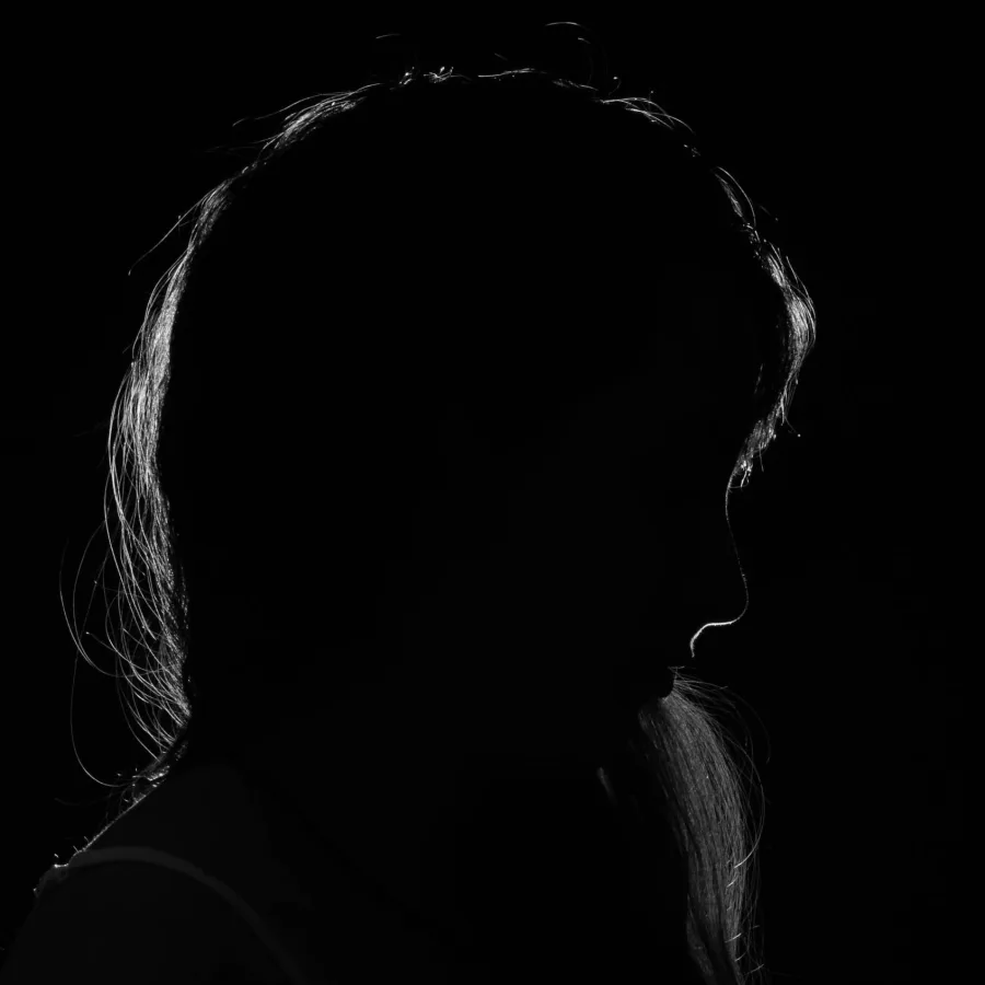A silhouette in profile in near darkness, the face not visible