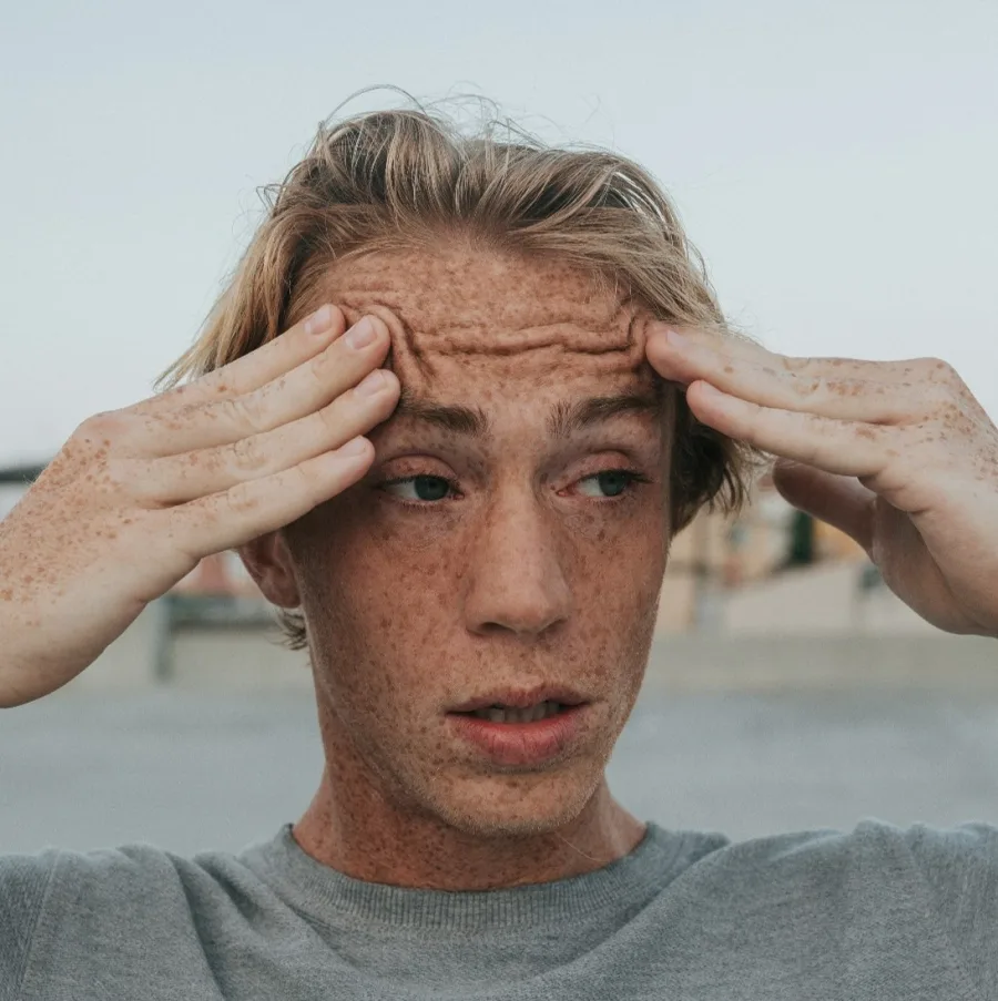 Young man with his hands to his temples, a worried look