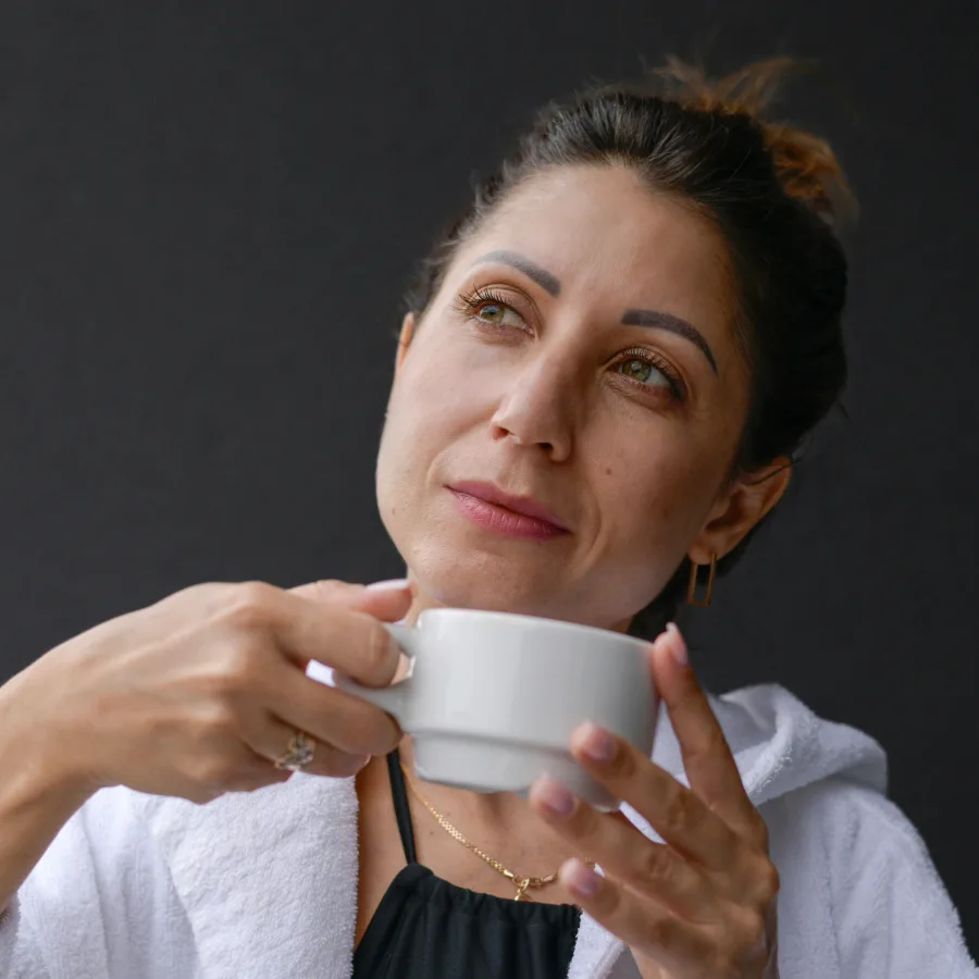 Mujer junto a una ventana abierta, postura relajada, luz natural
