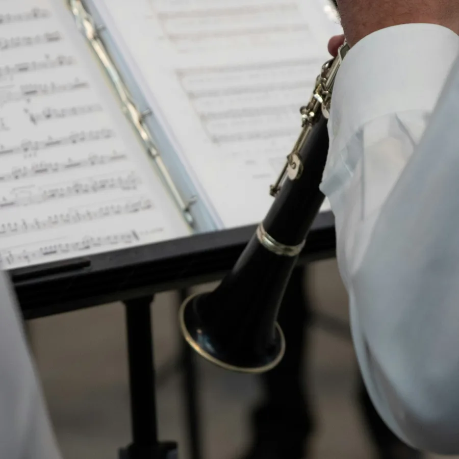 Clarinetista de espaldas tocando ante un atril y su partitura