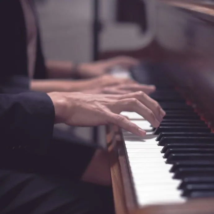 Manos de un pianista sobre el teclado, encuadre cerrado de perfil