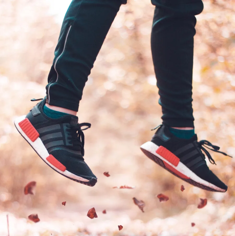 Zapatillas de correr en pleno salto sobre hojas de otoño