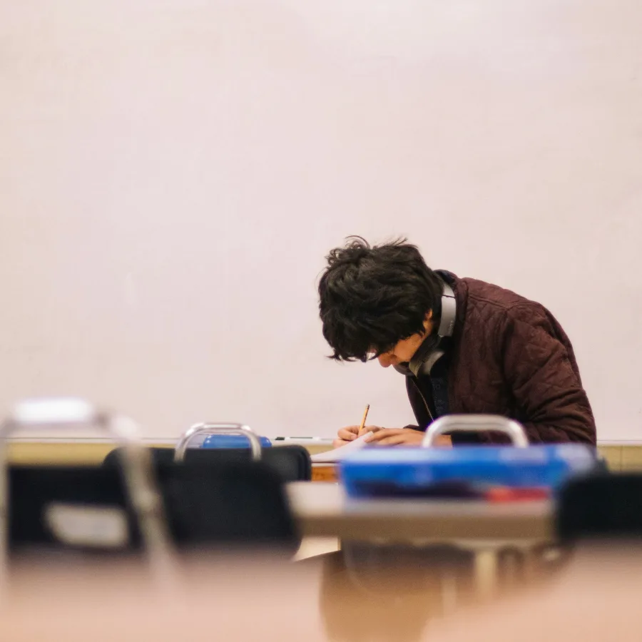 Adolescente inclinado sobre su trabajo en un aula, con el rostro oculto por el pelo