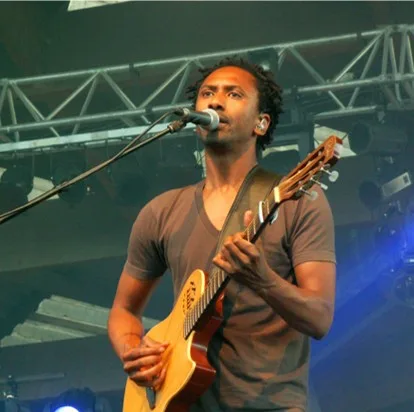 Daby Touré en escena, guitarra en mano, ante un micrófono