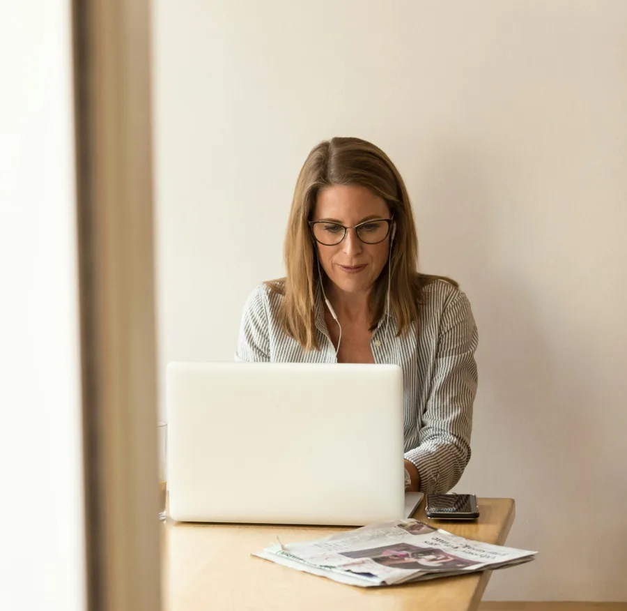 A woman alone at a table, concentrating on her laptop