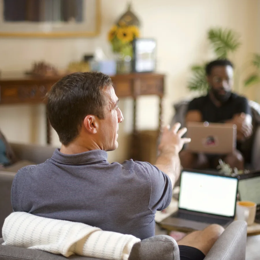 Two colleagues talking, seated, laptops open