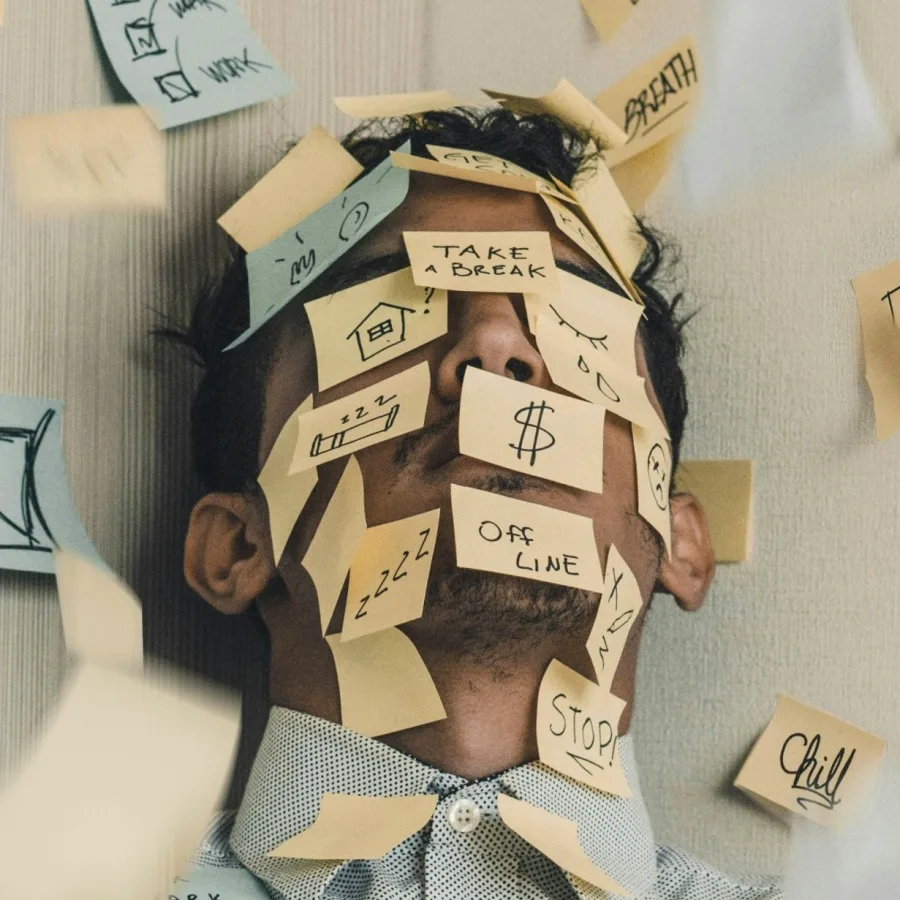 A man leaning back against a wall, his face covered in sticky notes