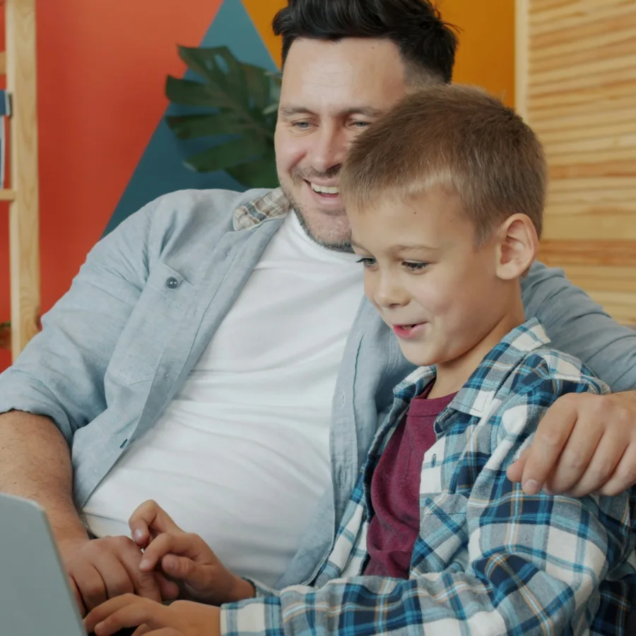 Smiling child in front of a screen, a relaxed parent alongside