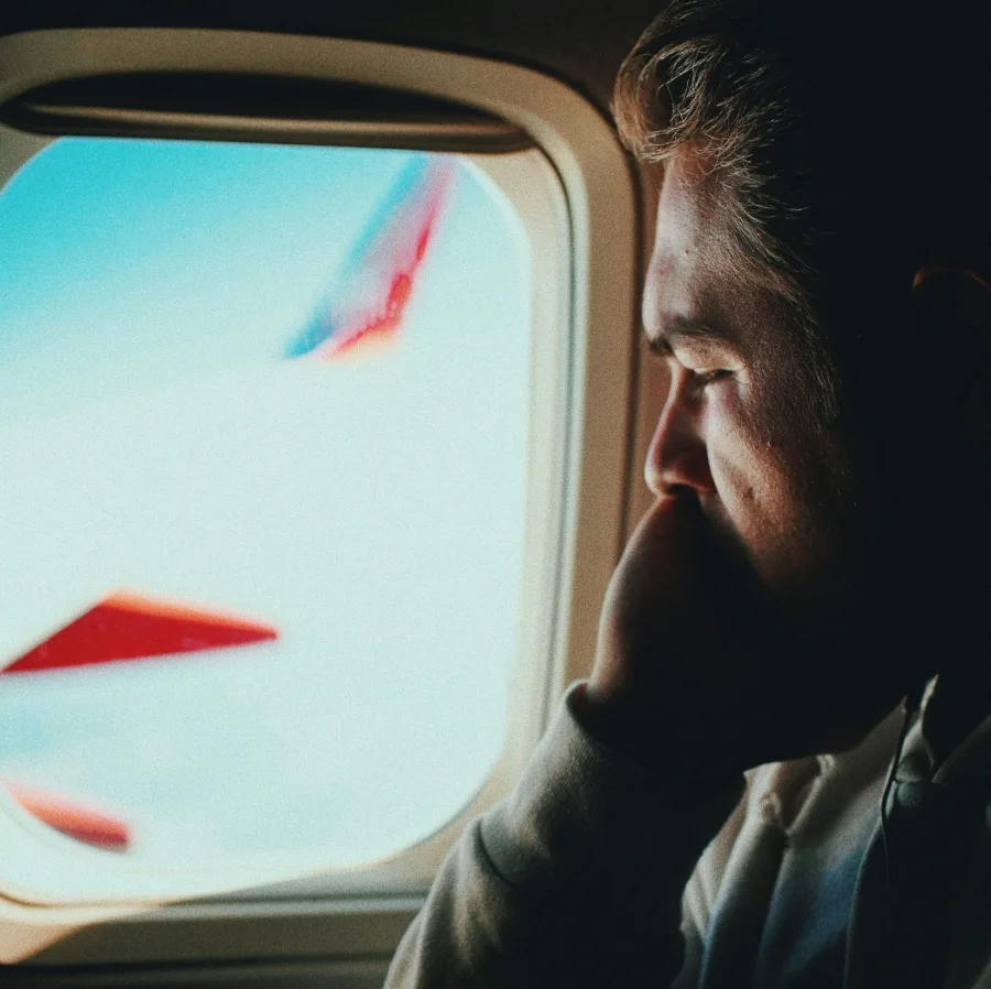 Pasajero pensativo mirando por la ventanilla de un avión