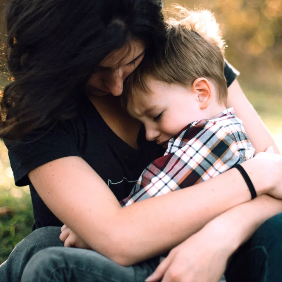 Mère serrant son jeune fils contre elle, à l'extérieur
