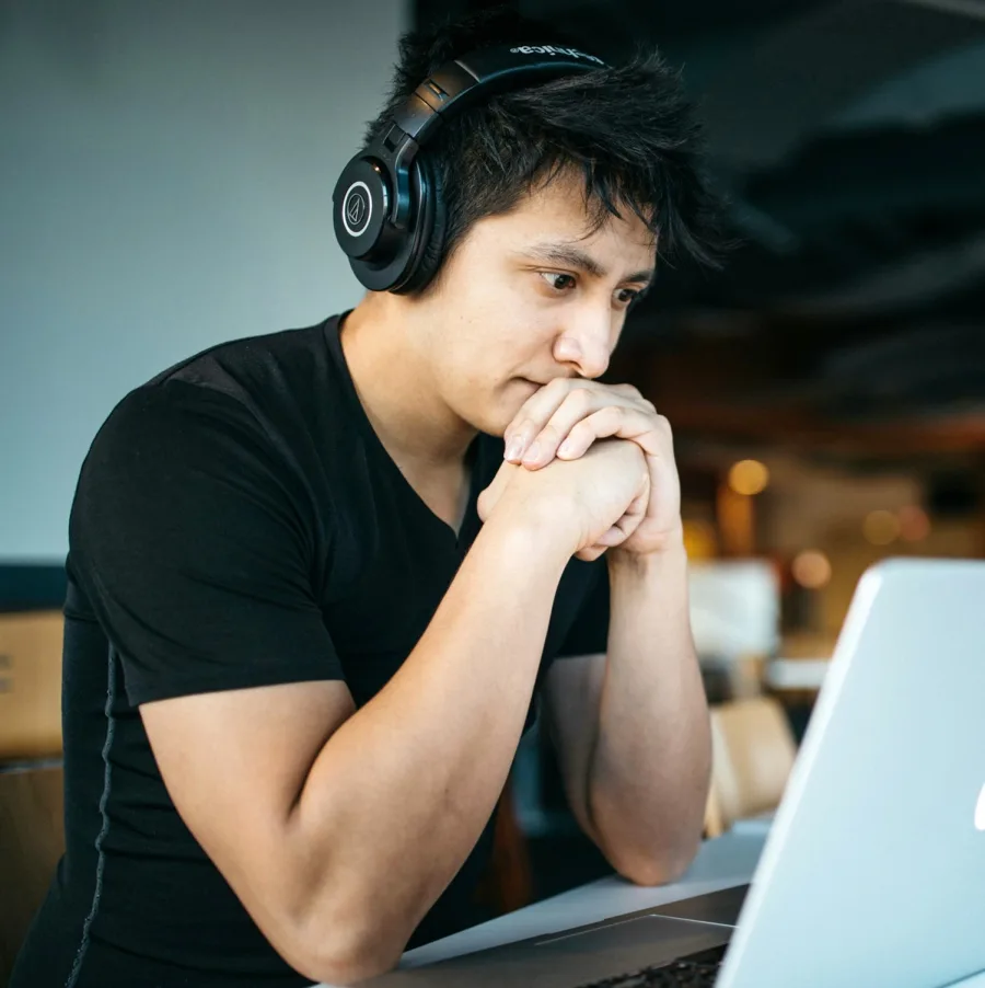Estudiante concentrado ante un ordenador portátil, con auriculares