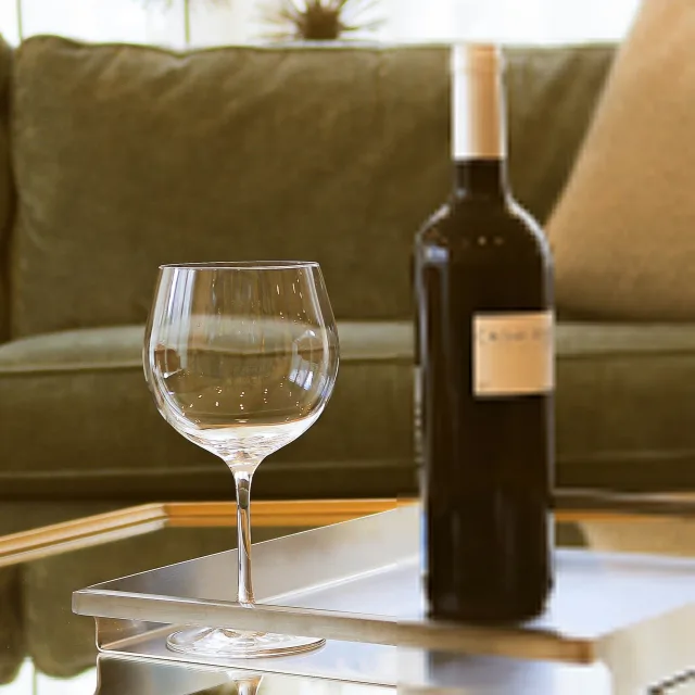 A wine bottle and an empty glass on a side table at the end of the day