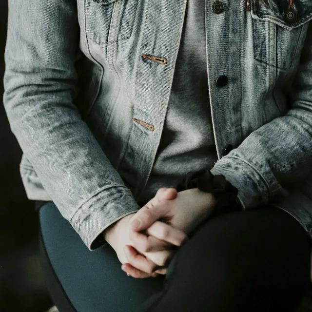 Hands clenched together, denim jacket