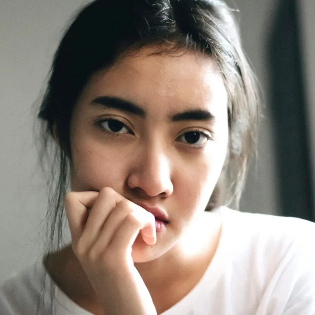 Young woman biting a nail, looking worried