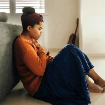 Personne assise, main posée sur le ventre