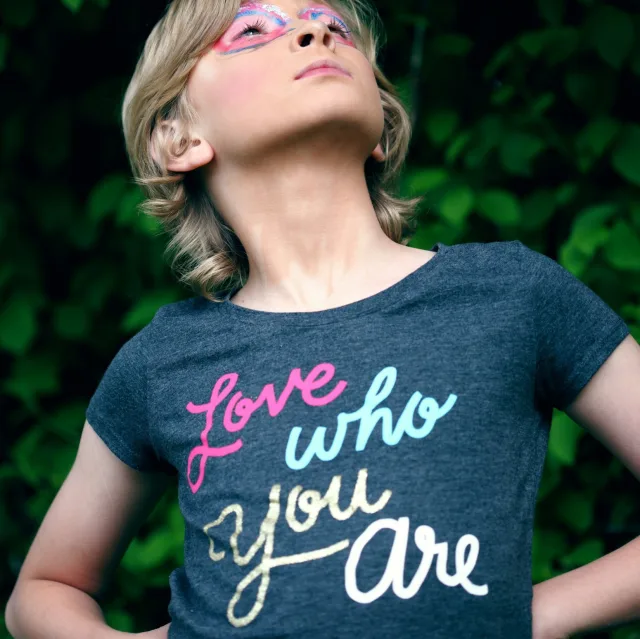 Proud child, head raised, wearing a "Love who you are" T-shirt