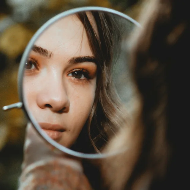 Reflet d'un visage dans un petit miroir rond, regard scrutateur
