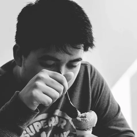 Adolescent mangeant une glace avec avidité