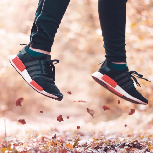 Person leaping energetically into autumn leaves