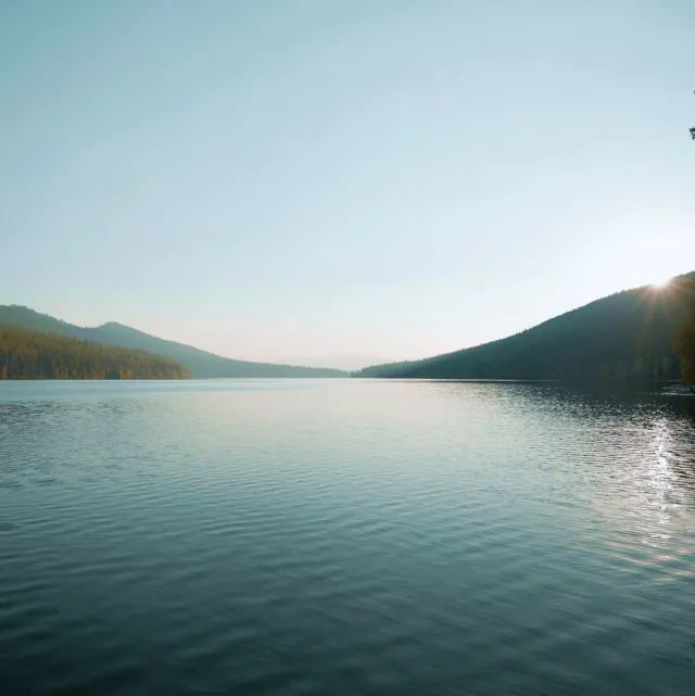 Calm lake at sunrise, surrounded by mountains