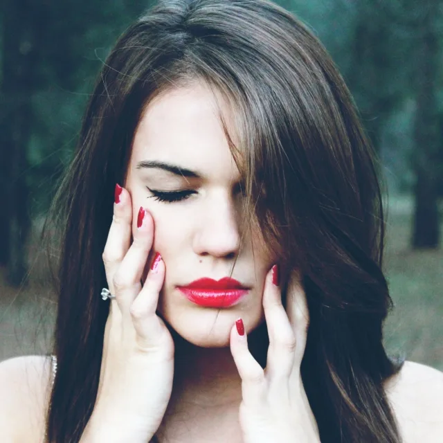 Woman pressing her temples with her fingertips, face tense