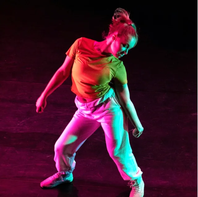 Dancer mid-performance, lit by coloured stage lights