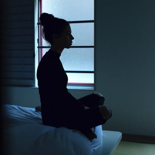 Figure sitting awake in the dark at night