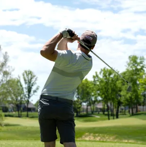 Golfeur vu de dos, en plein élan sur un parcours bordé d'arbres
