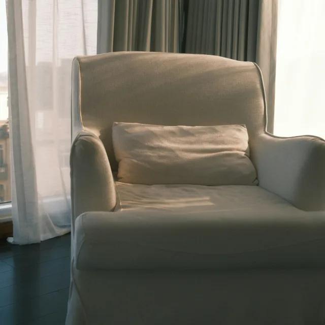 Un fauteuil clair près d'une fenêtre, dans une lumière douce