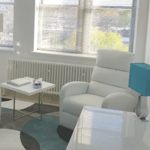 Sala de consulta luminosa, sillón blanco junto a un gran ventanal