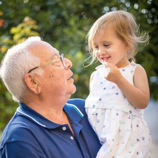Un grand-père et sa petite-fille souriants, se regardant