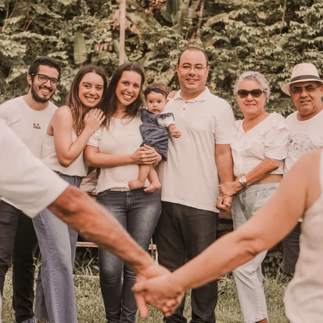 Three generations together outdoors, hands joined in the foreground